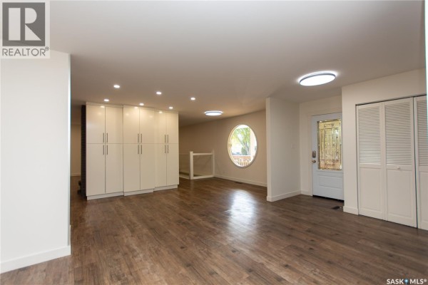 Interior view of an open-concept living space with laminate flooring and white cabinetry. - 10710 Meighen Crescent, North Battleford