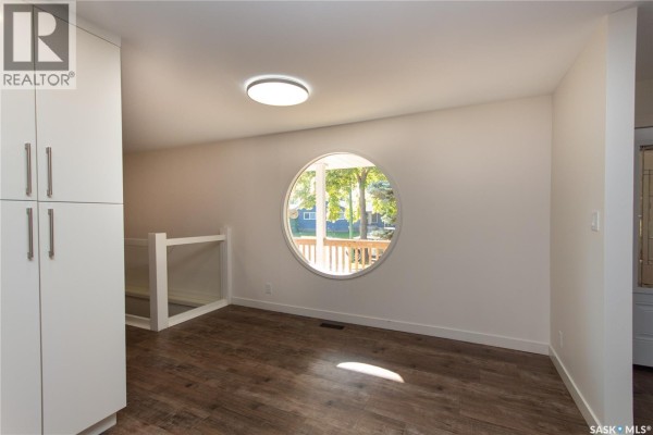 Interior view of a room with a large, circular window and a staircase railing. - 10710 Meighen Crescent, North Battleford