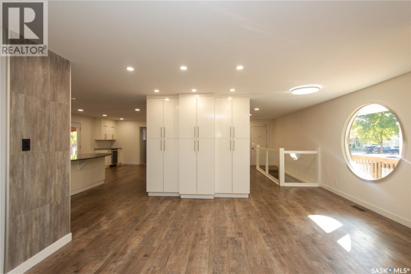 Interior view of a spacious room with laminate flooring and built-in white storage cabinets. - 10710 Meighen Crescent, North Battleford