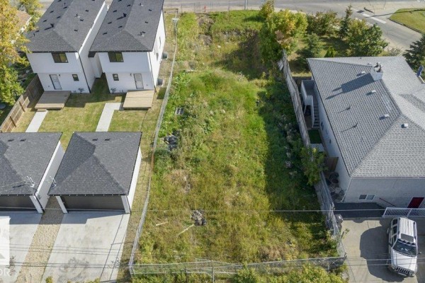Aerial view looking down at the fenced-off vacant lot between contemporary townhouses and a single-family home. - 10712 149 St Nw, Edmonton