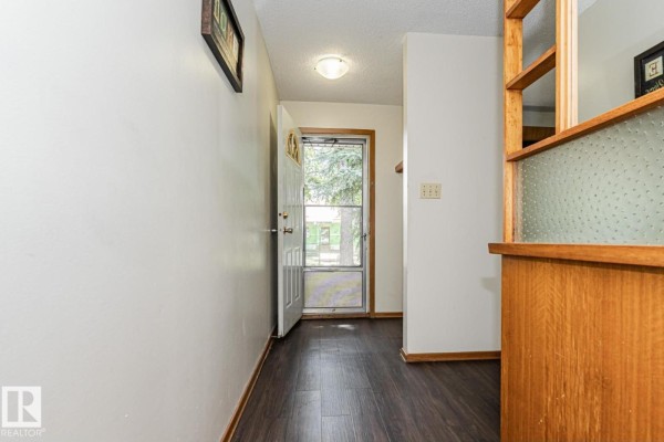 Interior entryway with white walls, dark wood laminate flooring, and a built-in wooden shelf. - 10726 70 Av Nw, Edmonton