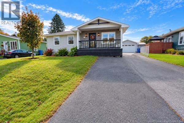 Front exterior view of a grey house with a porch, driveway, and lawn. - 1073 Rockland Drive, Bathurst