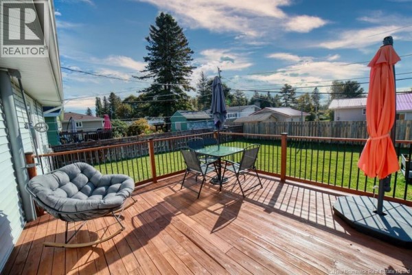 Wooden deck with outdoor furniture, overlooking a fenced backyard. - 1073 Rockland Drive, Bathurst