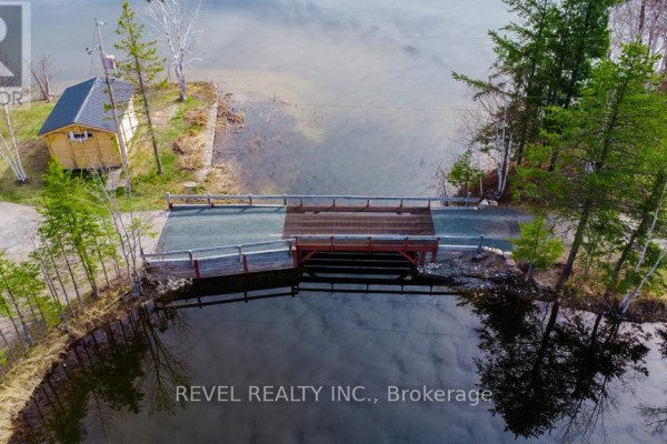 View of a large house by the water with a dock and reflections in the lake. - 1075 Cameron Avenue, Iroquois Falls