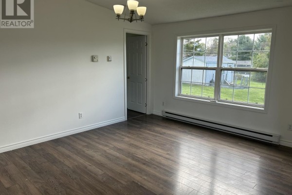 Living room with dark wood laminate flooring, white walls, and a large window facing outdoors. - 1075 Waddens Court, Westville