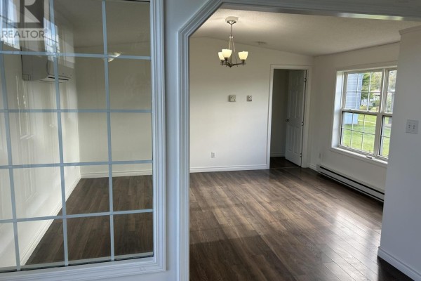 View from entryway looking into a living area with dark wood laminate flooring and white walls. - 1075 Waddens Court, Westville