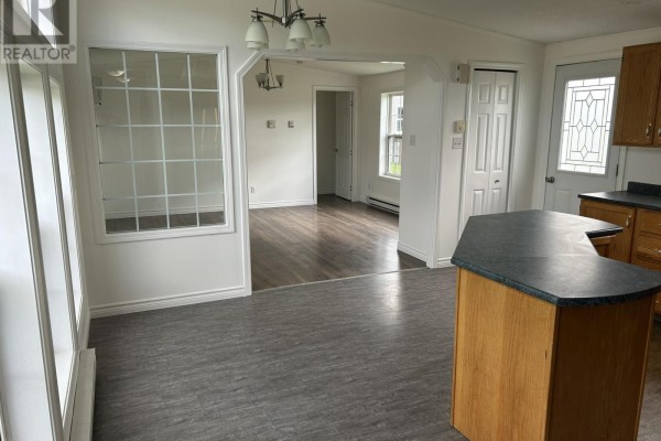 Open concept living and kitchen area with dark grey flooring and light wood cabinetry. - 1075 Waddens Court, Westville
