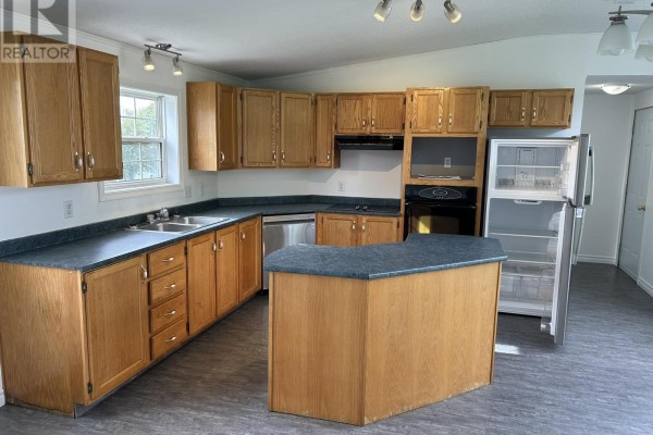 Kitchen with light wood cabinets, dark countertops, stainless steel appliances, and an island. - 1075 Waddens Court, Westville