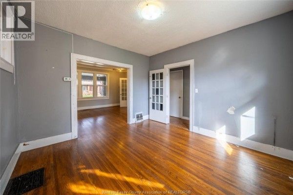 View from the living room into another room, featuring hardwood floors and double doors with glass panes. - 1076 Dougall Avenue Unit# Main, Windsor