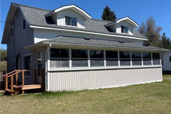Side view of a light grey house with a large screened-in porch and dormer windows. - 1076 Howard Rd, Howard