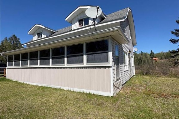 Corner view of the light grey house showing the screened-in porch and dormer windows. - 1076 Howard Rd, Howard