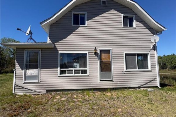 Rear exterior of the house with two doors, windows, and satellite dishes mounted on the wall. - 1076 Howard Rd, Howard