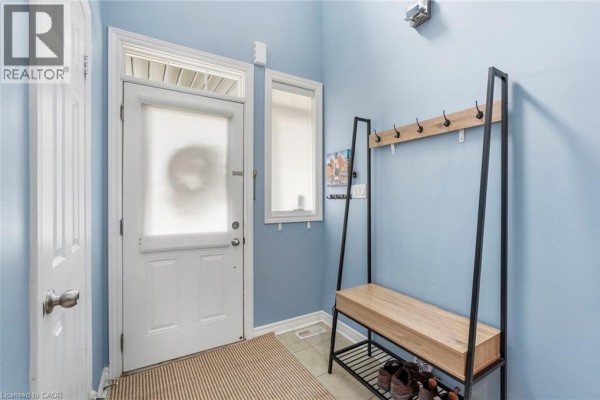 Interior entryway with light blue walls, white door, and wood bench with coat rack. - 1076 Ryckman Common, Burlington