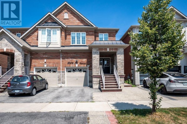Front exterior of a brick house with stone accents and a three-car garage. - 1079 Job Crescent, Milton