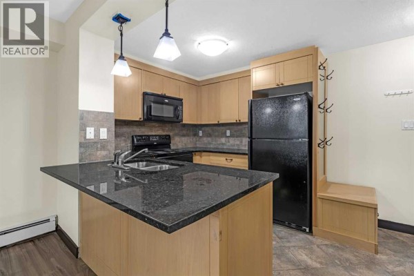 Entryway with a dark brown door, coat hooks, and a bench with storage. - 108, 315 50 Avenue Sw, Calgary