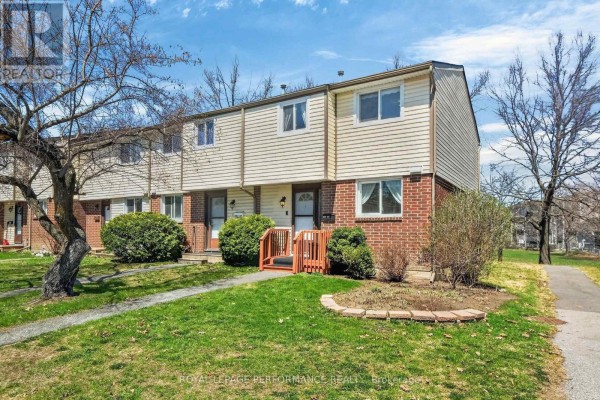 Row of townhouses with manicured lawns and mature trees in front. - 108 - 1389 Palmerston Drive, Ottawa