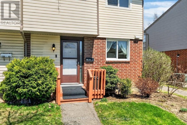 Close-up of the townhouse entrance with a red wooden door and steps. - 108 - 1389 Palmerston Drive, Ottawa