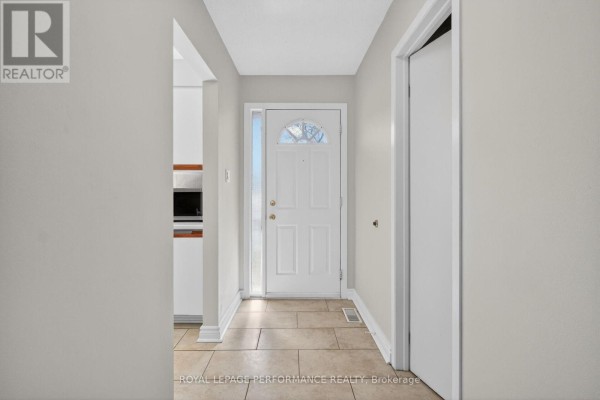 Interior view of a hallway with a white front door and tiled floor. - 108 - 1389 Palmerston Drive, Ottawa
