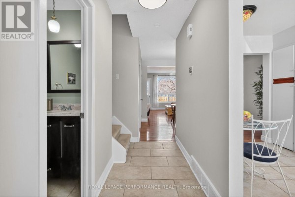Hallway with tiled floor leading to living areas and stairs, plus a small powder room. - 108 - 1389 Palmerston Drive, Ottawa