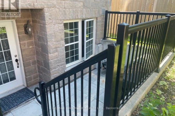 Entrance door with white windows and black railing on a stone facade exterior. - 108 - 1485 Birchmount Road E, Toronto