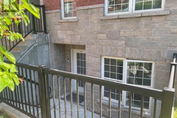 Lower level entrance with a glass sliding door and windows on a stone facade. - 108 - 1485 Birchmount Road E, Toronto
