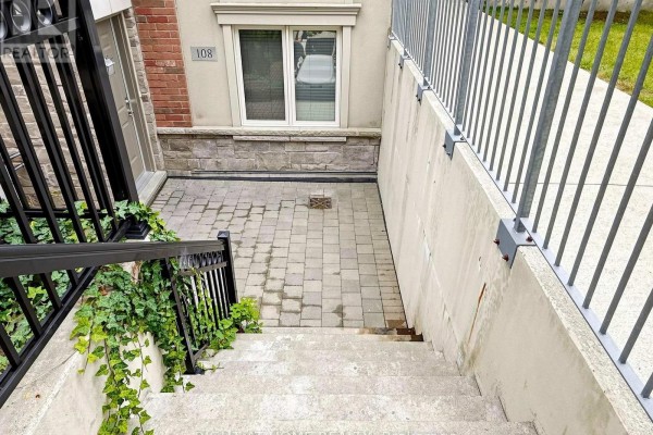 View looking down concrete stairs to a paved patio and entrance. - 108 - 17 Coneflower Crescent, Toronto
