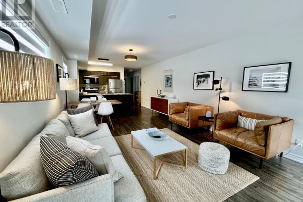 Cozy living space featuring a sectional sofa, coffee table, and kitchen view - 108 - 2 Cove Court, Collingwood