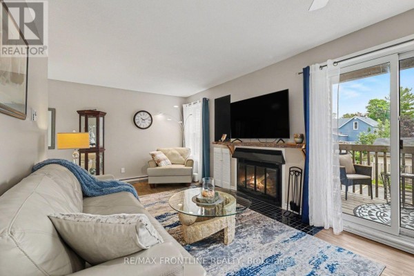 Living and dining area with a beige sofa, wooden dining table and chairs, and beige walls. - 108 - 24 Townline Road, Carleton Place
