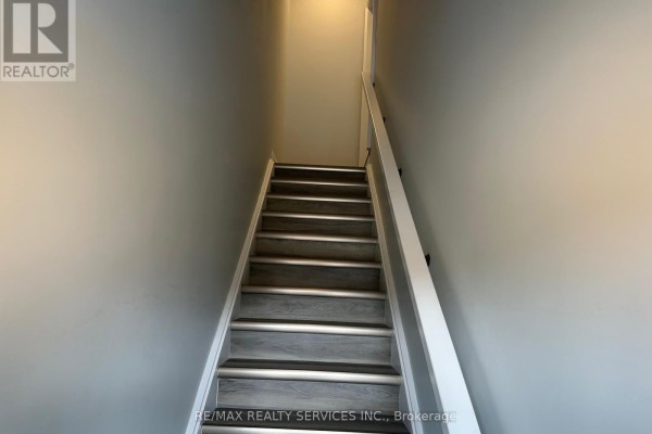 Carpeted staircase with wood-look treads and white handrails ascends between gray walls. - 108 - 361 Quarter Town Line, Tillsonburg