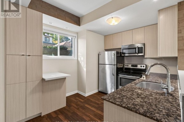 Kitchen with light wood cabinets, granite countertops, stainless steel appliances, and dark wood floor. - 108 - 400 Hopewell Avenue, Toronto