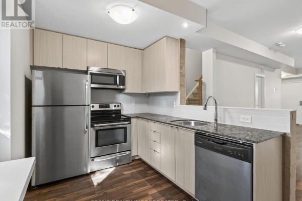 Kitchen with light wood cabinets, granite countertops, stainless steel appliances, and dark wood floor. - 108 - 400 Hopewell Avenue, Toronto