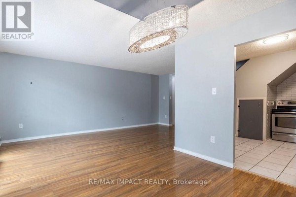 Dining area with wood floors, light blue walls, and a view into the kitchen. - 108 - 454 Centre Street, Oshawa