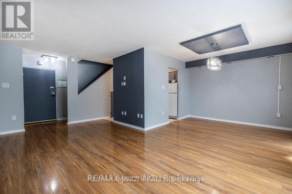 View of the main living area with wood floors, grey walls, and stairs leading up. - 108 - 454 Centre Street, Oshawa