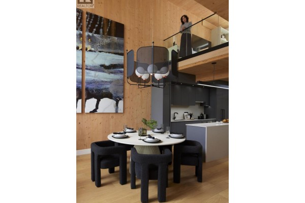 Round dining table with black chairs, abstract art, and a view of the kitchen. - 108 310 Salter Street, New Westminster