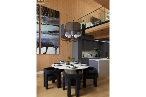 Dining area with view of loft and kitchen, featuring dark chairs and a white table. - 108 310 Salter Street, New Westminster