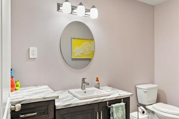 Powder room with a dark wood vanity, white square sink, marble countertop, and toilet. - 108 Country Drive, Torbay