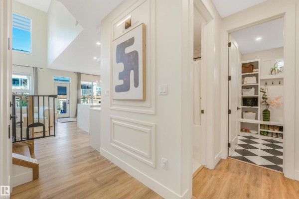 Interior hallway with wood floors, white wainscoting, abstract art, and a view into a mudroom. - 108 Edgefield Wy, St  Albert