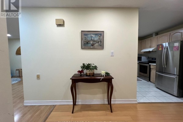 Entrance hallway with a wooden console table and a framed picture on a cream-colored wall. - 108 Freshmeadow Drive, Toronto