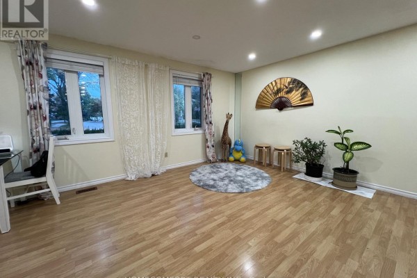 Living room with large windows, beige walls, wood floors, and decorative items. - 108 Freshmeadow Drive, Toronto
