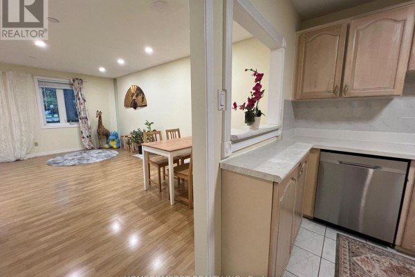 View from the kitchen pass-through window to a dining area with a table and chairs. - 108 Freshmeadow Drive, Toronto