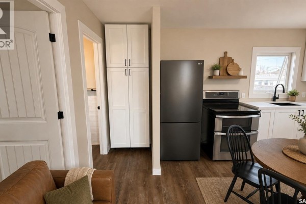 Kitchen area with dark stainless steel appliances, white cabinetry, and black countertop. - 108 Front Street N, Pense