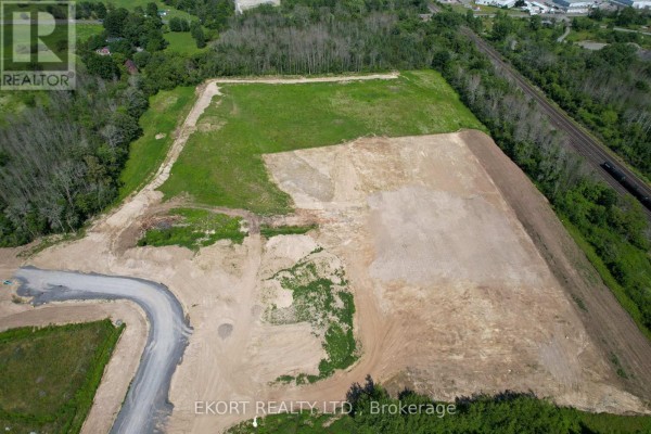 Aerial view of vacant land with cleared area, surrounded by trees and road access. - 108 Huff Avenue, Quinte West