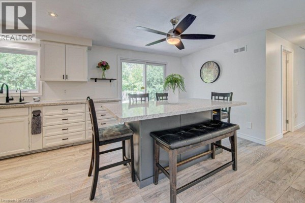 Kitchen with white cabinets, granite countertops, and a central island with seating for three. - 108 Lake Road, Puslinch