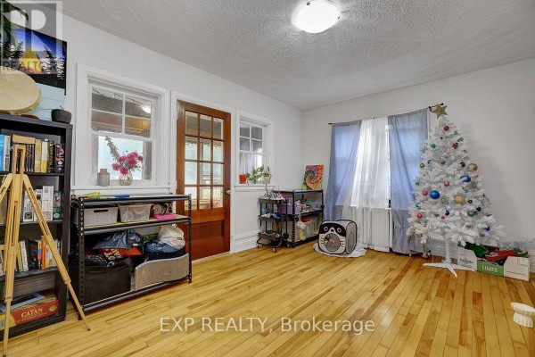 Living area with wooden floors, windows, a bookshelf, and a white Christmas tree. - 108 Lebreton Street N, Ottawa