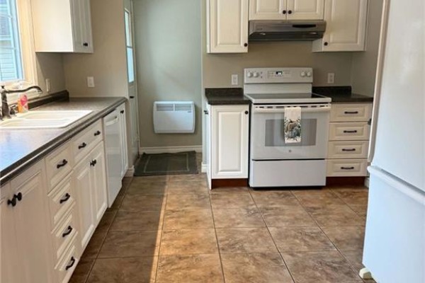 Interior entryway with tiled floor, wooden staircase, chest of drawers, and open front door with screen. - 108 Stothart Drive, Miramichi