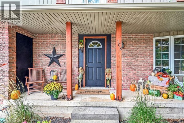 Covered front porch with brick facade, dark blue door, and seating. - 108 Temperance Street E, Waterford