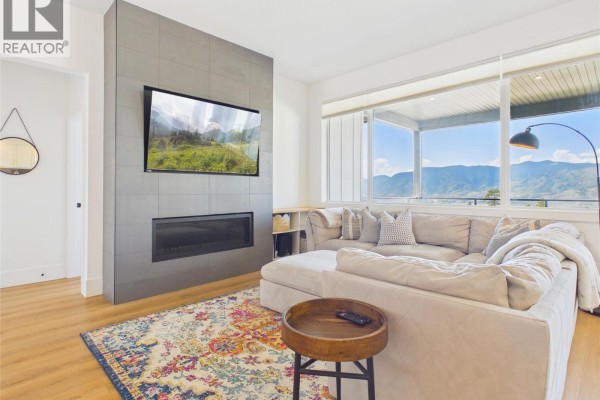 Entryway with built-in bench, coat hooks, mirror, and view of living and kitchen areas. - 1081 Antler Drive, Penticton