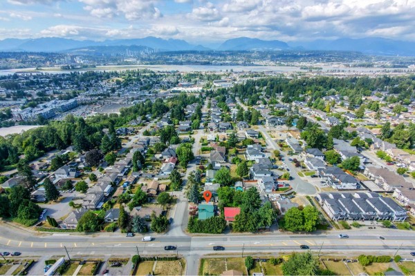 Distant aerial view of a suburban area showing houses, roads, and the city skyline with a suspension bridge. - 10810 129 Street, Surrey