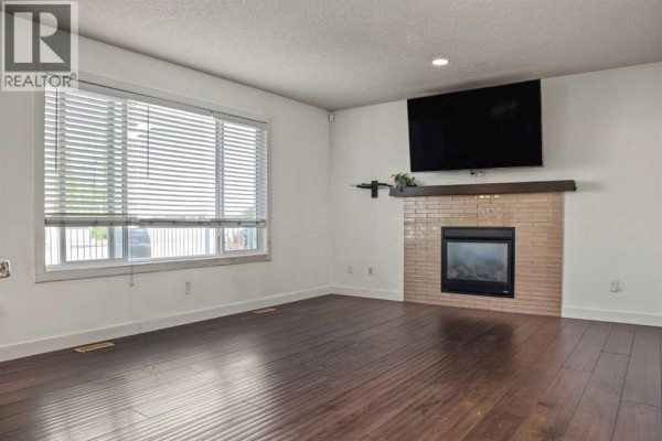 Side entrance of a house with grey siding, a white door, and stairs leading to the front. - 10821 60a Avenue, Grande Prairie