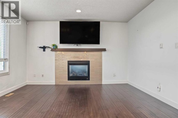 Interior staircase with a vaulted ceiling, carpeted stairs, and dark wooden railings. - 10821 60a Avenue, Grande Prairie